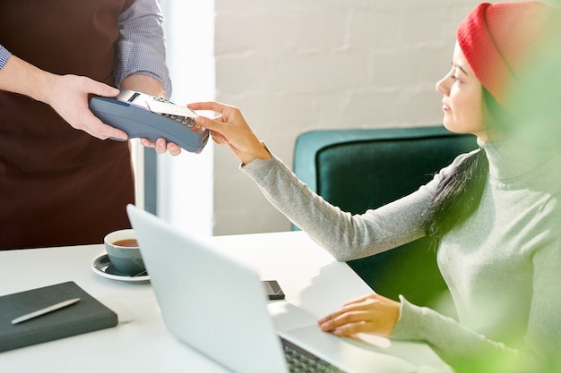 Jeune femme payant par carte de crédit