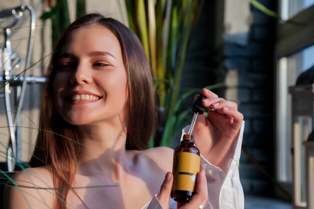 Jeune femme avec une peau parfaite et fraîche posant au bain dans la salle intérieure de la salle de bain avec de l'huile. Concept de cosmétologie et de traitement. Concepts publicitaires de mode de vie sain, de SPA et de soins personnels. Espace de copie