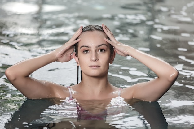 Jeune femme avec une peau parfaite se détendre dans la piscine