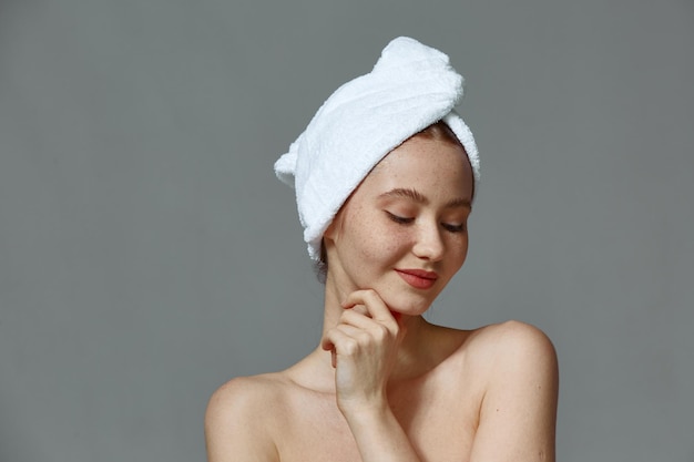 Jeune femme avec une peau de visage parfaitement lisse, des épaules nues, une serviette sur la tête, une beauté naturelle, des soins de la peau