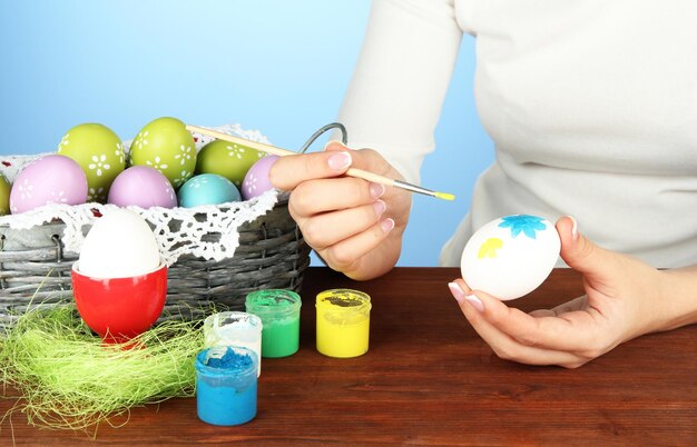 Jeune femme peignant des oeufs de pâques sur le fond de couleur