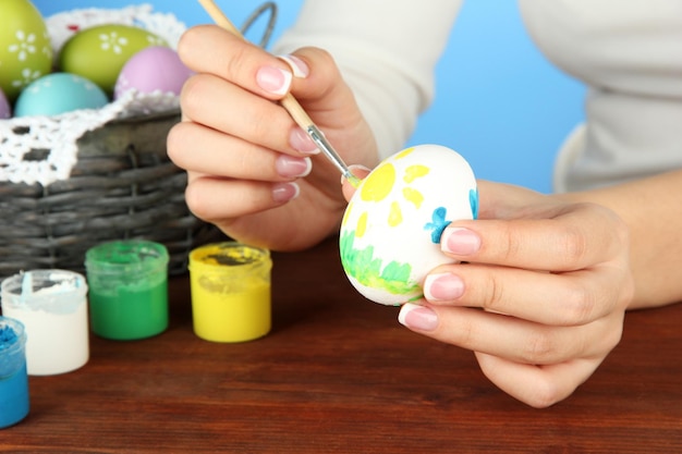 Jeune femme peignant des oeufs de pâques sur le fond de couleur