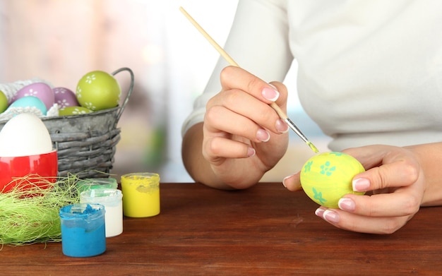 Jeune femme peignant des oeufs de pâques sur le fond lumineux