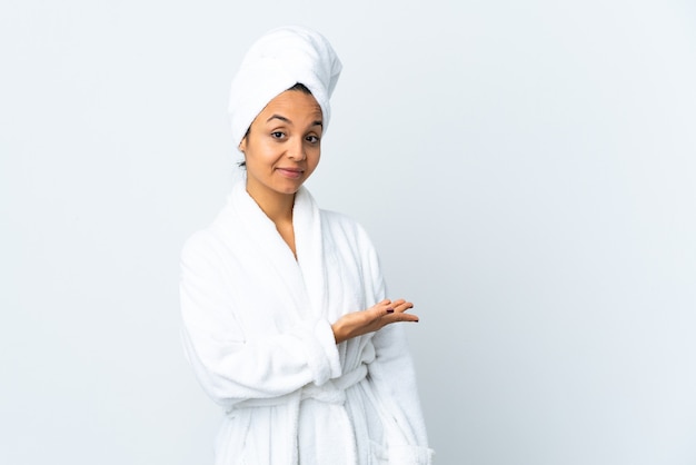 Jeune femme en peignoir sur blanc isolé présentant une idée tout en regardant en souriant vers