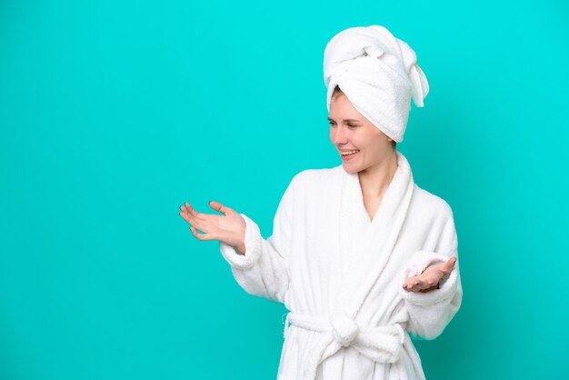 Jeune femme en peignoir isolé sur fond bleu avec une expression faciale surprise