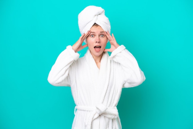 Jeune femme en peignoir isolé sur fond bleu avec une expression de surprise