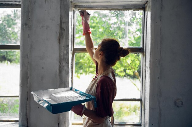 Photo une jeune femme peint une fenêtre à la maison.