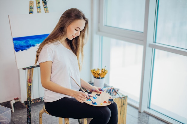 Jeune femme peintre peinture sur chevalet en atelier