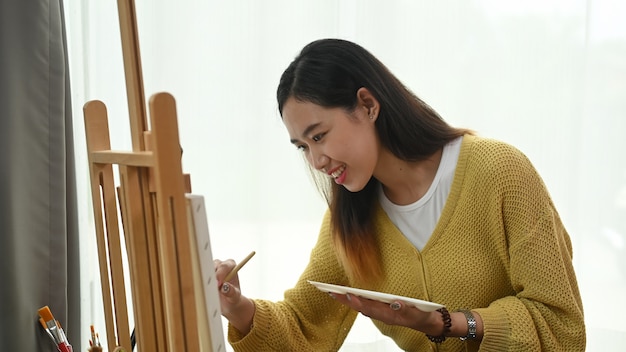 Jeune femme peinture sur une toile à la maison