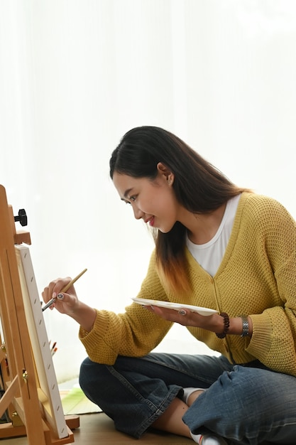 Jeune femme peinture sur une toile à la maison