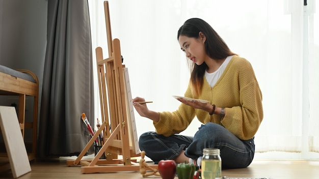 Jeune femme peinture sur une toile à la maison