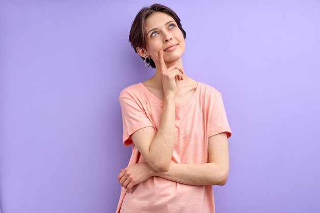 Jeune femme pensant à quelque chose proposer une idée dame aux cheveux courts en tenue décontractée en contemplation tenant le doigt sur le menton