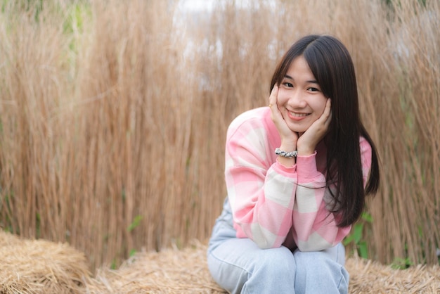 Jeune femme pensive assise dans les champs et pensant à l'avenir tout en regardant ailleurs