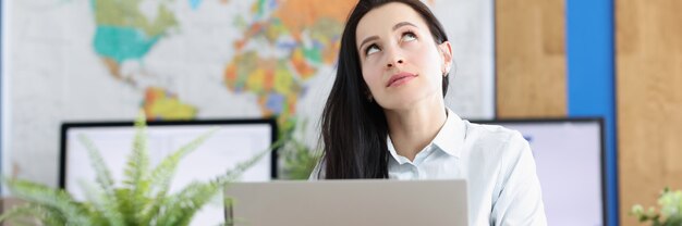 La jeune femme pensive s'assied à l'ordinateur portable et lève les yeux