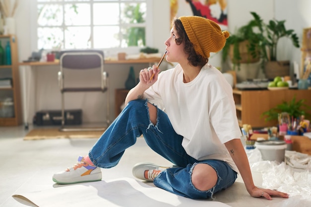 Jeune femme pensive en tenue décontractée tenant un crayon par la bouche