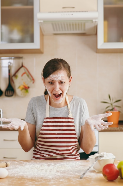 La jeune femme perplexe et confuse assise à une table avec de la farine et allant préparer des gâteaux dans la cuisine. Cuisiner à la maison. Préparer la nourriture.