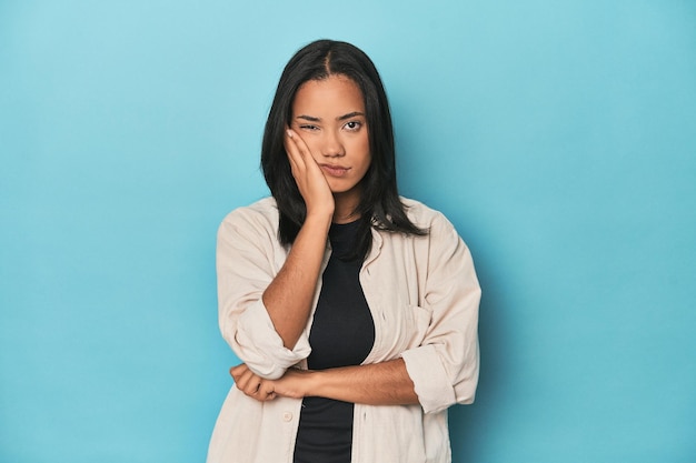 Une jeune femme philippine sur le studio bleu qui s'ennuie fatiguée et a besoin d'une journée de relaxation