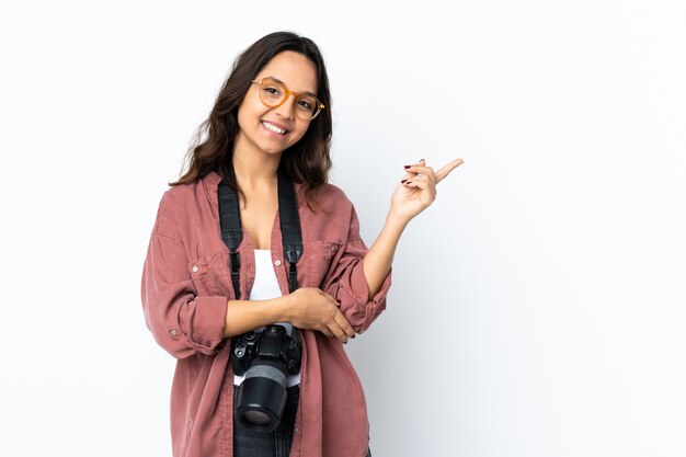 Jeune femme photographe sur blanc isolé heureux et pointant vers le haut