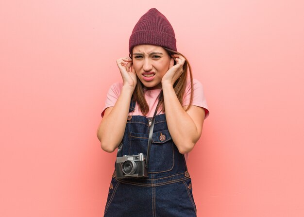 Jeune femme photographe mignon couvrant les oreilles avec les mains