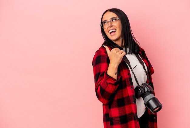 Jeune femme de photographie caucasienne avec un bras isolé sur des points de fond rose avec le pouce loin, riant et insouciant.