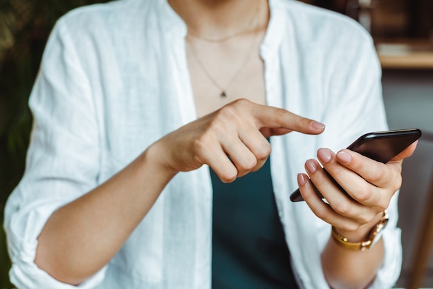 Jeune femme pigiste réussie pointant vers le téléphone. Envoi d'un message à un partenaire commercial