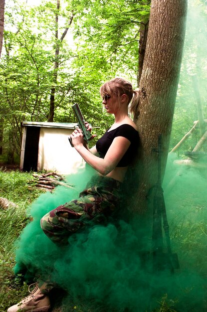 Photo une jeune femme avec un pistolet dans la forêt.