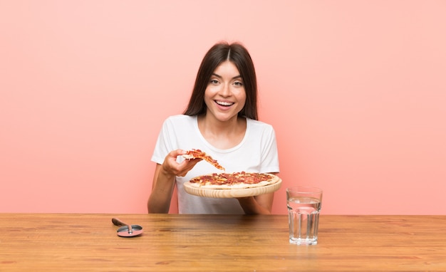 Jeune femme avec une pizza dans une table