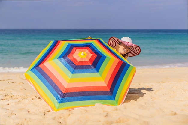 Jeune femme sur la plage dans un chapeau et un parasol