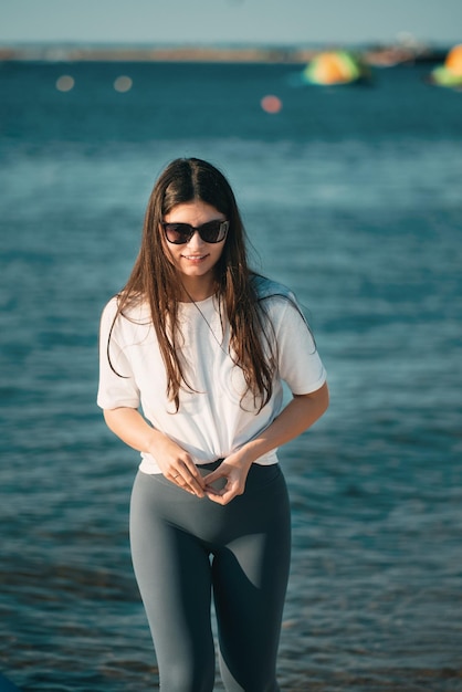 Jeune femme sur la plage avec de longs cheveux Fit belle fille porte une chemise blanche et des leggings gris sur la plage