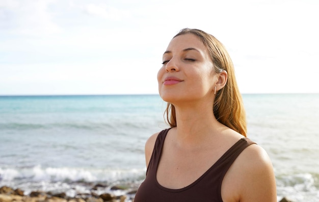 Jeune femme sur la plage en respirant profondément en profitant de la liberté de l'air frais