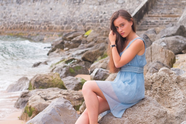 Jeune femme à la plage avec une robe turquoise.