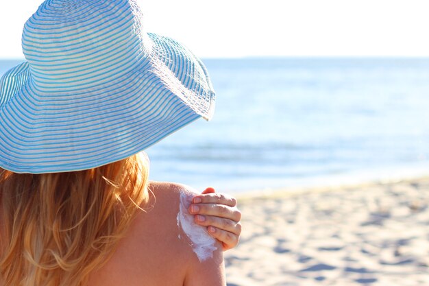 Jeune femme sur la plage utilise un écran solaire