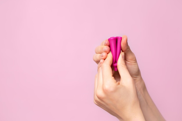 Une jeune femme pliant une coupe menstruelle rose dans sa main Fond de couleur rose Espace pour le texte Cycle de santé des femmes en silicone écologique Photo de haute qualité