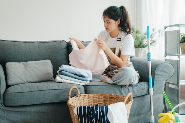 Jeune femme pliant des vêtements sur un canapé à la maison