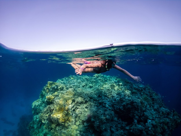 Jeune femme plongée en apnée dans les récifs coralliens de la mer Rouge