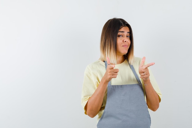 Jeune femme pointant quelque chose avec ses doigts sur fond blanc