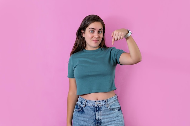 Jeune femme pointant vers le bas et regardant la caméra sur fond de bannière rose avec espace de copie