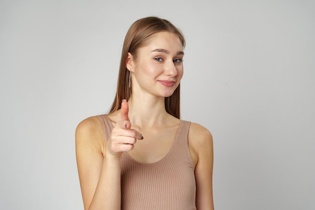 Une jeune femme pointant vers la caméra avec une expression ludique dans un studio