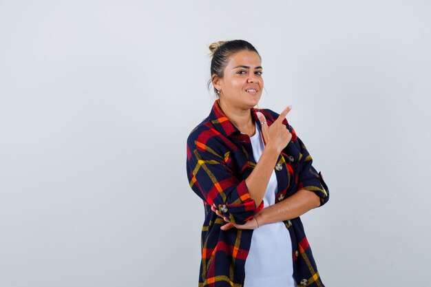 Jeune femme pointant vers le haut en chemise à carreaux et à la réflexion