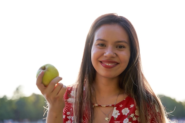 Jeune femme avec une pomme dans sa main femme avec des dents blanches parfaites souriant à la caméra