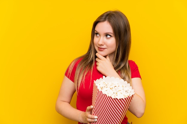 Jeune femme, à, pop-corn, mur rose, penser, a, idée