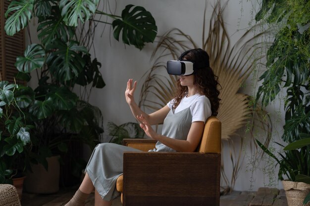 Jeune femme portant un casque VR faisant l'expérience de la réalité virtuelle tout en se reposant dans une serre