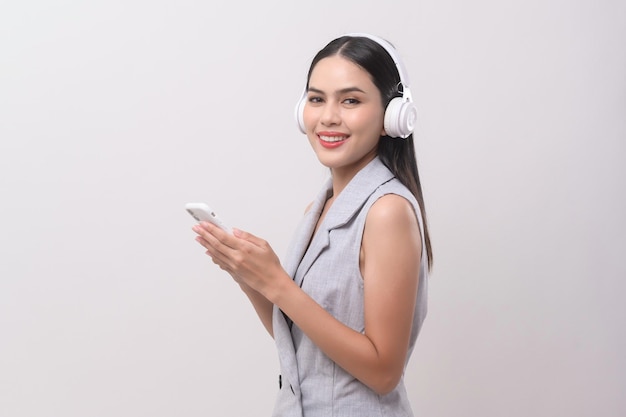 Une jeune femme portant des écouteurs profitant de la musique sur fond blanc