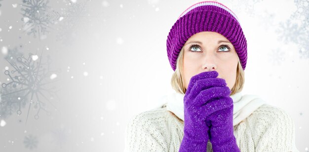 Jeune femme portant des gants de congélation regardant vers le haut contre le motif de flocon de neige