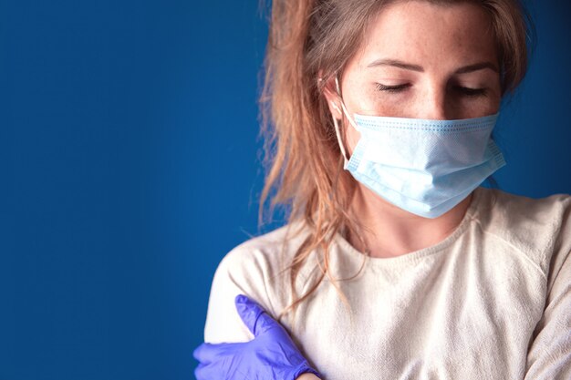 Jeune femme portant des gants de protection et un masque facial à l'intérieur d'une maison en quarantaine à l'ennui et triste, pour Covid-19 Coronavirus