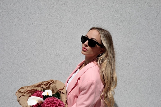 Photo une jeune femme portant des lunettes de soleil alors qu'elle se tient contre le mur