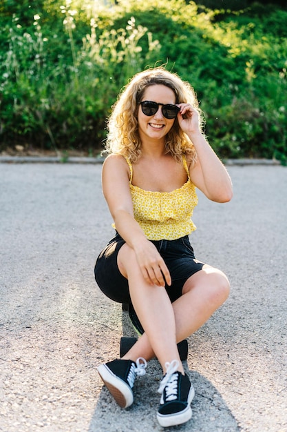 Une jeune femme portant des lunettes de soleil assise sur la route