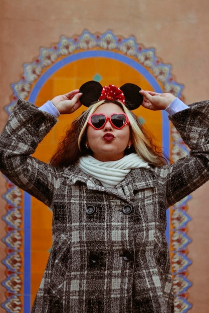 Photo une jeune femme portant des lunettes de soleil contre le mur.