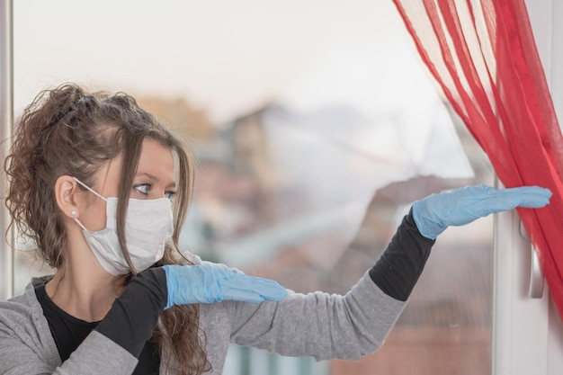 Photo une jeune femme portant un masque chirurgical et des gants fait des mouvements drôles avec ses mains.