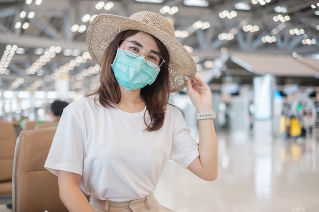 Jeune femme portant un masque facial à la protection de l'aéroport Infection par la maladie à coronavirus Voyageur asiatique Temps de voyage après le concept de dose de rappel de vaccin